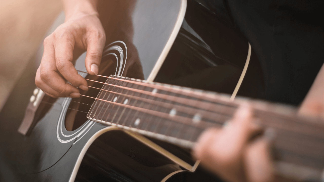 Person trying to improve finger dexterity by playing guitar with fingers