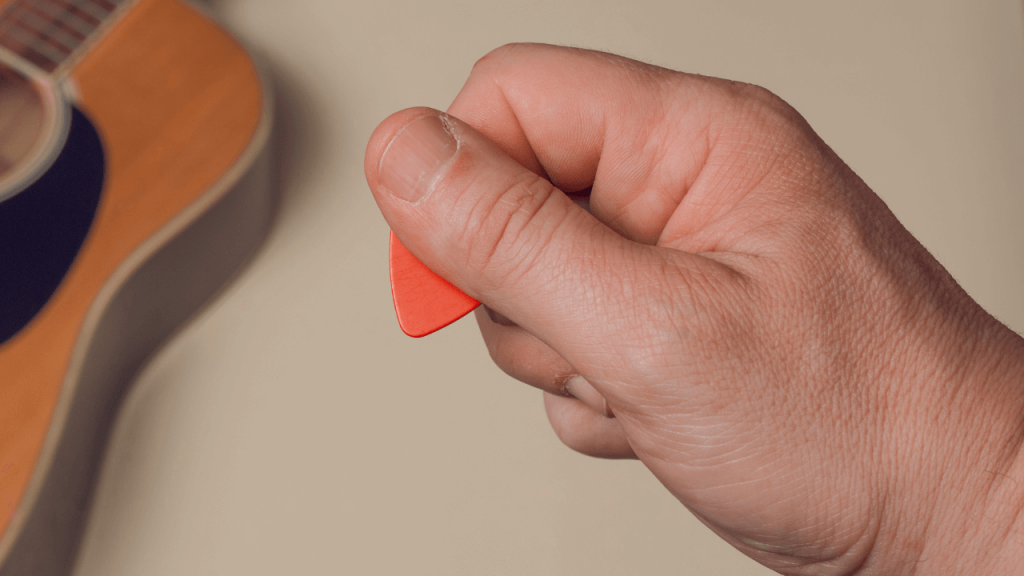 Close up of a hand holding a guitar pick the proper way