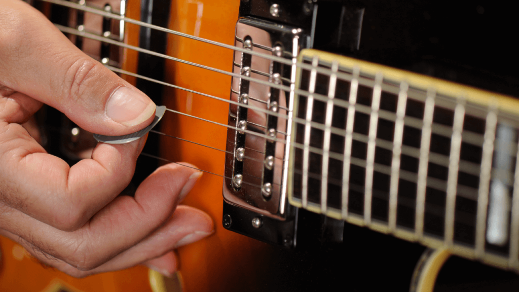 A person using a guitar pick to play guitar